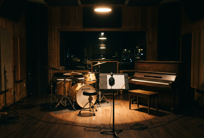 Empty recording studio live room with drum kit and piano under a single spotlight — AI Generated Image